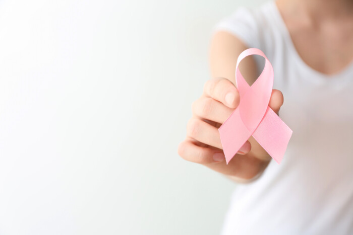 Woman Holding Pink Ribbon On Light Background, Closeup. Breast Cancer Awareness Concept