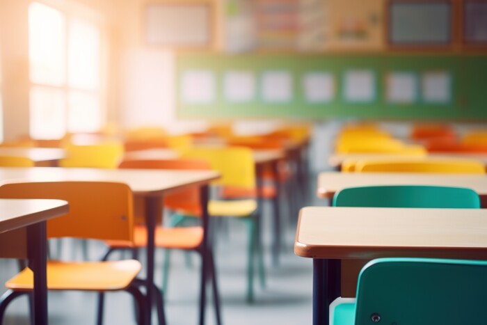 School Classroom In Blur Background Without Young Student. Blurry View Of Elementary Class Room No Kid Or Teacher With Chairs And Tables In Campus. Back To School Concept